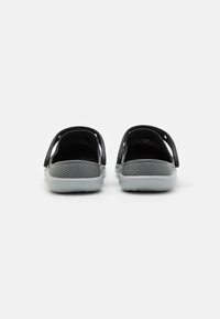 Fekete és szürke slip-on cipők texturált felsőrésszel, nyitott hátsó résszel és oldalsó vágásokkal a szellőzés érdekében. Simaságú talp, mintázott tapadással.