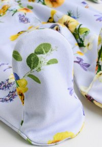 Tissu doux avec motif de feuilles vertes et de fleurs jaunes, violettes et blanches, conçu pour couvrir la main ou le pied.