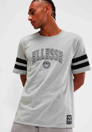 Camiseta de algodón gris con mangas cortas, acentos de rayas negras y un gran logo de "ELLESSE" en el pecho. Presenta una etiqueta de la marca en el dobladillo.