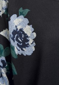 Svart tyg med stora blå och gröna blommönster, med en texturerad yta och mjuk känsla, perfekt för avslappnad klädsel.