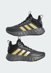 Black and gray athletic shoes with three gold stripes, mesh upper, padded collar, and textured black rubber sole.