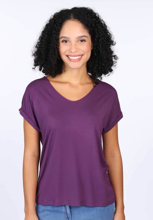 Lila kurzärmliges V-Ausschnitt-T-Shirt aus glattem Stoff, mit umgeschlagenen Ärmeln und lockerem Schnitt, getragen mit Jeans.