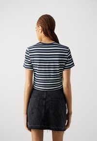 Marinblå och vit randig kort ärmad t-shirt som är cropad, ihopparad med en svart denim mini kjol med fransar i nederkant och bakfickor.