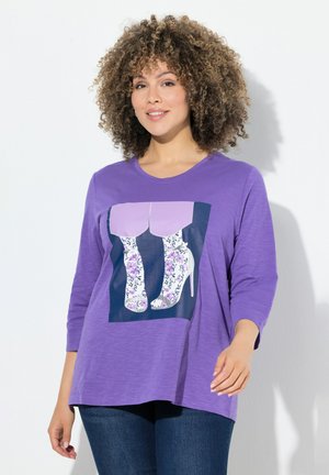 Lila Langarmshirt mit grafischem Druck von High Heels. Weicher Stoff, lässige Passform, runder Ausschnitt und strukturiertes Muster an den Ärmeln.