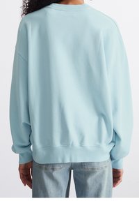 Light blue, oversized sweatshirt with a round neck, ribbed cuffs, and hem. Soft fabric with a smooth texture. Casual design.