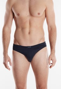 Boxers noirs en coton avec une texture de tissu lisse, dotés d'une large ceinture et de coutures minimales pour un ajustement épuré.