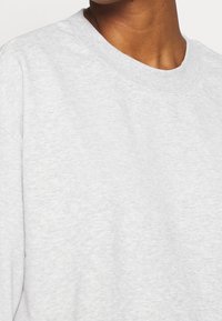 Sweat-shirt gris à col ras du cou, mélange de coton, texture lisse, coutures visibles, coupe décontractée, manches courtes, motif chiné subtil.