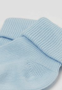 Světle modré pletené ponožky s ribovaným lemem a hladkou texturou, které předvádějí měkkou, elastickou tkaninu a jednoduchý design.