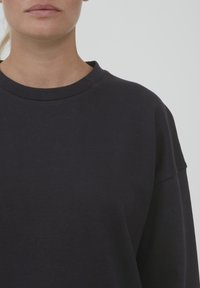 Felpa oversized blu navy con scollo rotondo, texture morbida e spalle cadenti, caratterizzata da un design semplice e senza cuciture.