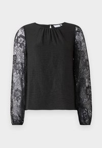 Svart langermet topp med teksturert stoff og ermer i blonder med blomster. Nøkkelhullslukking bak med en løkke. Elegant design og detaljerte aksenter.