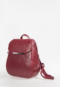 Leder-Rucksack in Burgunderrot mit Klappenverschluss, silberfarbenen Beschlägen, seitlichem Reißverschluss und verstellbaren Trägern. Glatte Textur, abgerundete Form.