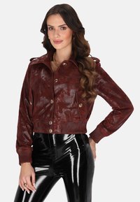 Zkrácená bordeaux bunda z lesklé ekokůže, s límečkem, předními knoflíky a pletenými manžetami, doplněná o černé lakované kalhoty.