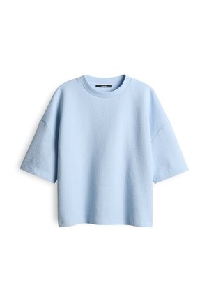 Light blue oversized t-shirt made of textured fabric with a round neckline and short sleeves. Features a relaxed fit and minimal design.