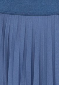 Tejido azul plisado con una cintura sólida, que muestra una fina textura de tejido en diagonal y pliegues verticales uniformes.