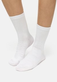 White crew socks made of soft material, featuring a ribbed texture and a cuffed top, with a smooth finish and no visible patterns.