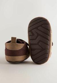 Chaussures pour enfants en brun et beige avec une tige en daim doux, une semelle en caoutchouc texturée et une languette au talon pour un enfilage facile.