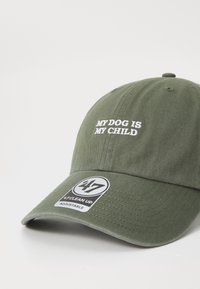 Casquette en coton vert avec le texte brodé blanc "MON CHIEN EST MON ENFANT", dotée d'une sangle réglable et d'un motif texturé hexagonal sur la visière.