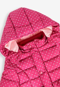 Różowa kurtka z wypełnieniem, w białe kropki, z kapturem i miękkim wykończeniem. Posiada zatrzaski i szczegóły w ribbanu przy kołnierzu.