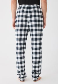 Herrepysjamasbukser med svart-hvitt rutemønster, elastisk midje, myk tekstur og løs passform, vist fra bak.