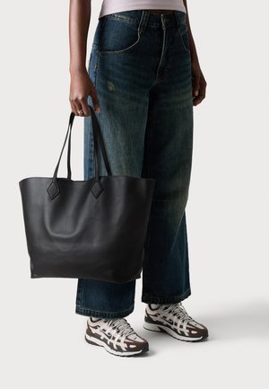 Black leather tote bag with a smooth texture and flat shape, featuring two elongated handles and a simple, unadorned design.