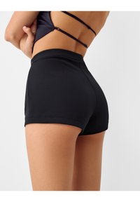 Svarta högmidjade shorts gjorda av töjbart material, med en enkel design, sidofickor och en sömfinish längs fållen.