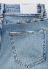 Lichtblauwe denim jeans met een enkele achterzak, zichtbare stiksels in een contrasterende oranje kleur en een witte geweven label op de tailleband.