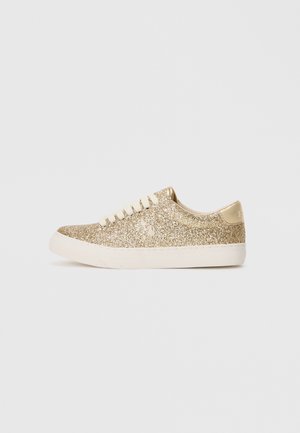 Baskets basses avec dessus en paillettes dorées, lacets blancs et semelle en caoutchouc blanche, présentées de profil sur fond uni.