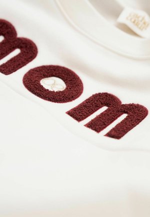 Weißer Sweatshirt mit burgunderfarbenen, strukturierten Buchstaben. Die Buchstaben sind plüschig und übergroß, mit einem kleinen, gestickten Markenlogo.