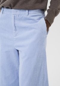 Lichtblauwe corduroy broek met verticale ribbels, met een klassieke pasvorm, zijzakken en een tailleband met riemlussen.