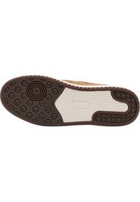 Sneaker-Außensohle mit einer strukturierten braunen Gummibasis, die kreisförmige Griffmuster aufweist, und einer weißen Zwischensohle. Deutlich sichtbares Markenlogo.