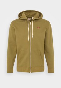 Felpa con zip color verde oliva, dotata di cappuccio con cordino, tasche frontali e un piccolo logo rosso di Levi's sulla parte superiore del lato sinistro del petto. Tessuto morbido.