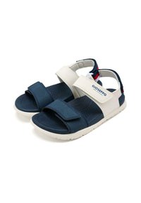 Sandalias en azul marino y blanco con correas de velcro, plantilla texturizada y suela de goma ligera. Presentan un logo en el lateral y acentos en contraste.