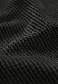Tissu en velours côtelé noir avec des côtes verticales distinctes et une surface douce et texturée formant des plis légers.
