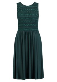 Robe sans manches en vert foncé avec un corsage en dentelle texturée présentant des motifs en zigzag ; jupe fluide en tissu doux.