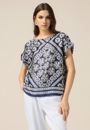Haut à imprimé floral bleu marine à manches courtes, doté d'un motif géométrique et d'une coupe ample. Tissu doux avec une bordure texturée.