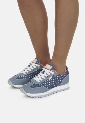 Zapatillas de lona azules con lunares blancos, cordones blancos, suela gris claro y detalles en rosa en el talón y la lengüeta.
