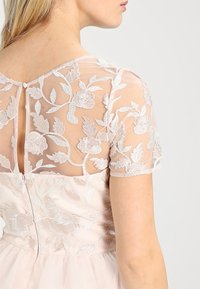 Light pink formal dress with a sheer embroidered back and short sleeves, featuring floral patterns and a keyhole closure.
