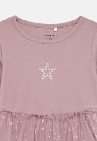 Ροζ ψηλόμεσο φόρεμα με στρογγυλή λαιμόκοψη. Στραφταλιστή λεπτομέρεια αστεριού στο μπροστινό μέρος και φούστα από τούλι με μοτίβα αστεριών στο κάτω μέρος.