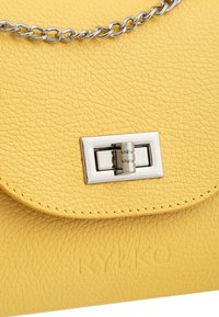 Borsa a tracolla gialla in pelle con finitura texture, chiusura magnetica e tracolla in catena argentata. Presenta un marchio impresso sulla parte frontale.