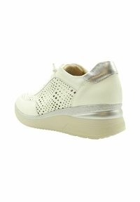 Zapatilla blanca de cuero con detalles perforados, acentos plateados en el talón y suela de goma beige. Punta redondeada y diseño con cordones.