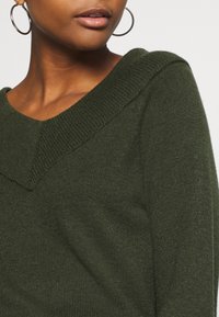Dark green knit sweater with a wide V-neckline and ribbed texture, featuring a fitted silhouette and soft fabric.