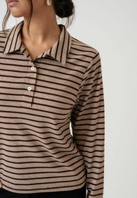 Polo majica dugih rukava u smešnim i bež trakama, sa ovratnikom, plaketom na tri dugmeta i mekanim, teksturiranim materijalom.