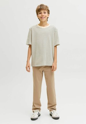 Bombažna majica z belimi in mornarsko modrimi črtami, kombinirana z bež hlačami. Lahka, sproščena majica z kratkimi rokavi in okroglim izrezom.
