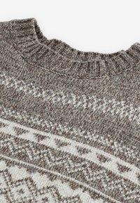 Pull en maille marron et blanc avec un col rond côtelé et un motif géométrique sur la poitrine.