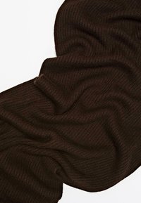 Coperta lavorata a maglia di colore marrone scuro con una superficie testurizzata, caratterizzata da una caduta ondulata e un aspetto morbido. Adatta per il calore e per essere sovrapposta.