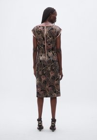 Lillatrükiga kleit lühikeste varrukatega, keha järgiva lõikega, musta taustaga ja roosakuldsed aktsendid. Tagaküljel on lukk ning kleidi pikkus on põlveni.