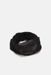 Fascia nera realizzata in morbido tessuto, con una patch lucida di colore marrone scuro che riporta il testo "HUGO" in nero, design attorcigliato per una vestibilità sicura.