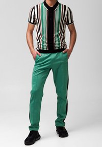 Poloko s krátkým rukávem se svislými pruhy v černé, zelené, hnědé a krémové barvě, spárované s mentolově zelenými slim-fit kalhotami s černými postranními pruhy.