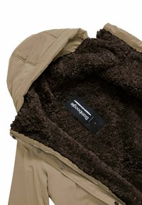 Beige hoodie met een bruin donzige fleece voering en een zwart "Bombboogie" merklabel binnenin de kraag.