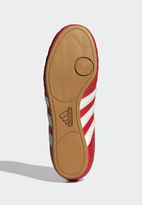 Sarkanais sporta apavu zole ar teksturētu rakstu, ar trim baltām svītrām un gumijas ārējo zoli. Logo iespiests sānos.
